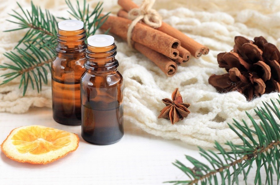 Essential oil surrounded by orange, cinnamon and conifers.
