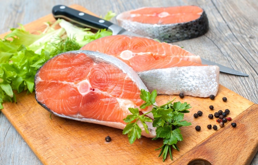 Salmon fillets in slices on a cutting board.