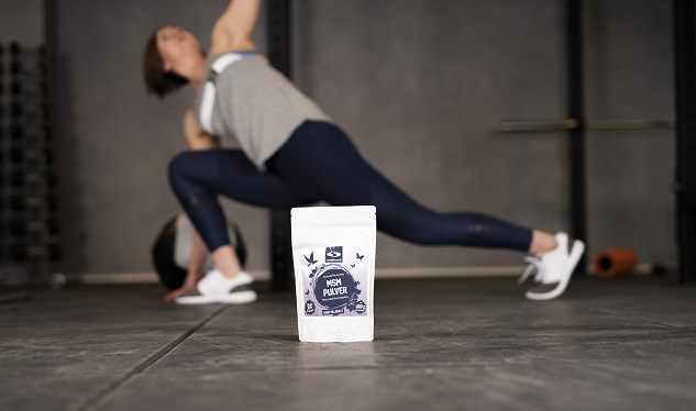 Person performing yoga exercise and MSM powder in the foreground.