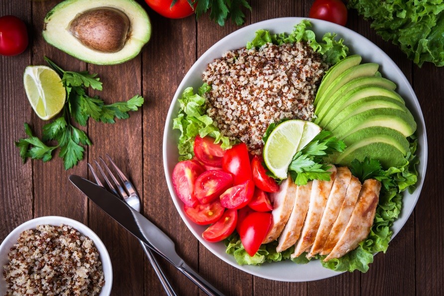 A meal with quinoa, vegetables, chicken and avocado.