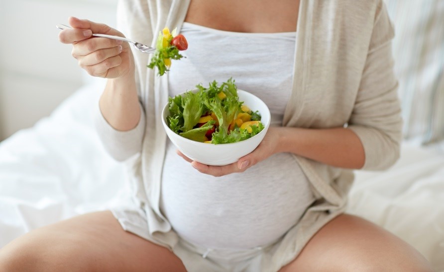 Pregnant woman eating salad.